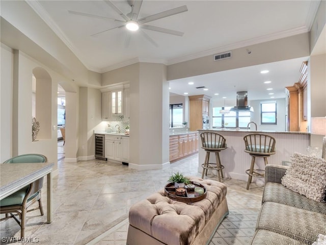 living room featuring crown molding, beverage cooler, and sink