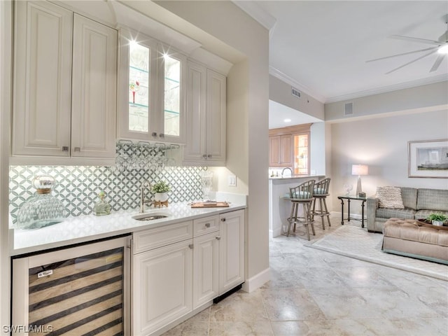 bar with sink, ornamental molding, beverage cooler, decorative backsplash, and white cabinets