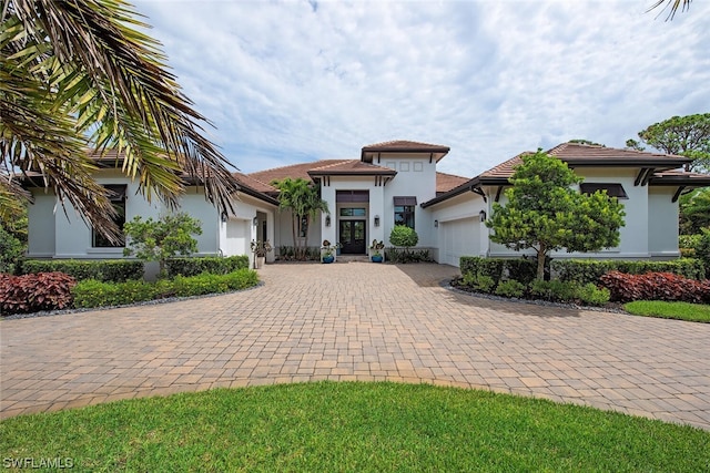 view of front of property with stucco siding, decorative driveway, and a garage
