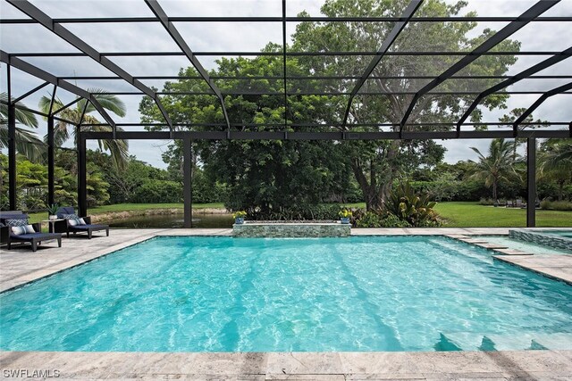view of swimming pool featuring a patio, a lawn, a pool with connected hot tub, and a lanai