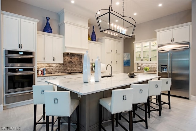 kitchen featuring a sink, white cabinetry, a warming drawer, and appliances with stainless steel finishes