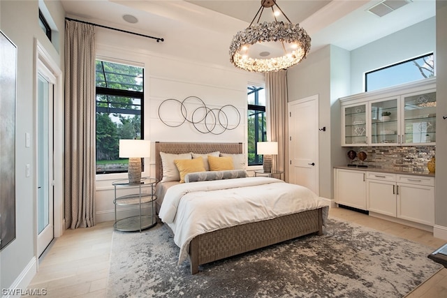bedroom featuring light wood finished floors, multiple windows, and a notable chandelier