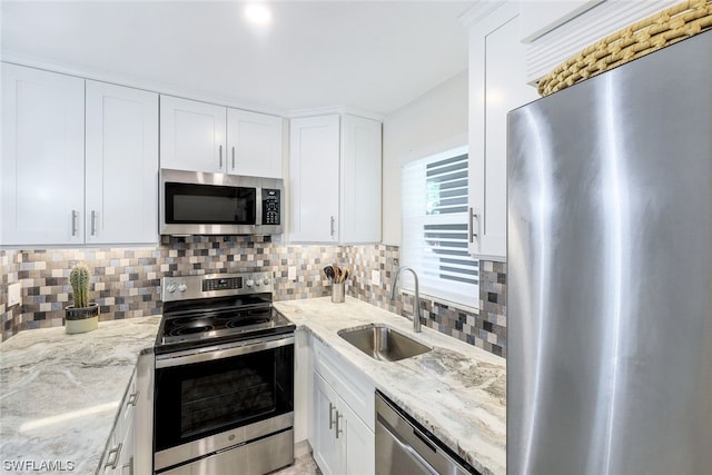 kitchen featuring white cabinetry, appliances with stainless steel finishes, light stone countertops, and sink