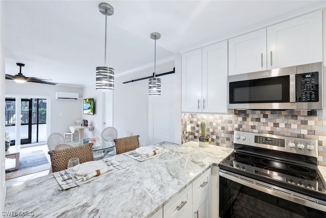 kitchen featuring pendant lighting, ceiling fan, a wall mounted AC, appliances with stainless steel finishes, and white cabinetry