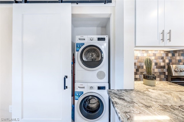 washroom with a barn door and stacked washer / drying machine