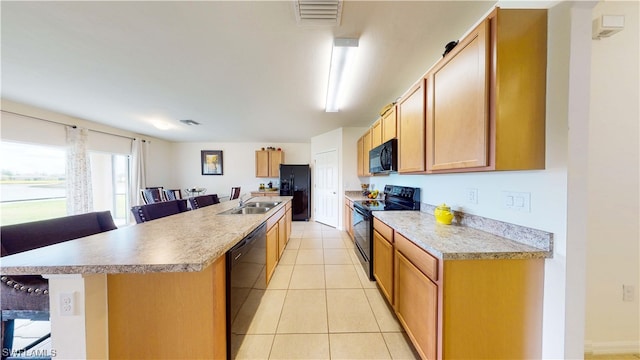 kitchen featuring a kitchen bar, light tile flooring, sink, and black appliances