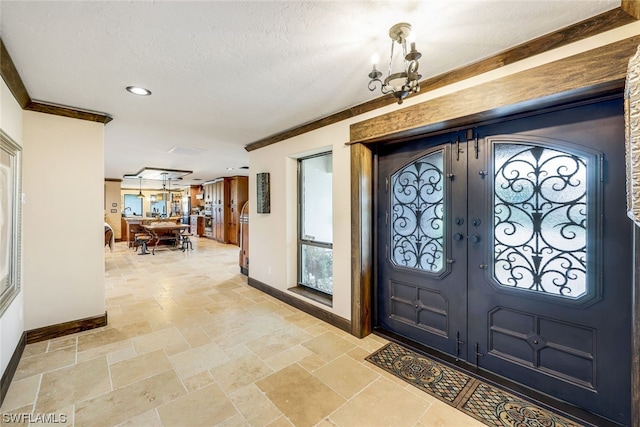 entryway featuring ornamental molding, french doors, a chandelier, and a textured ceiling