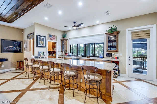 kitchen with a kitchen island, light stone countertops, plenty of natural light, and a kitchen bar