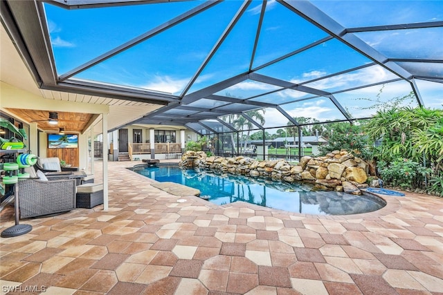 view of swimming pool featuring ceiling fan, outdoor lounge area, glass enclosure, and a patio area