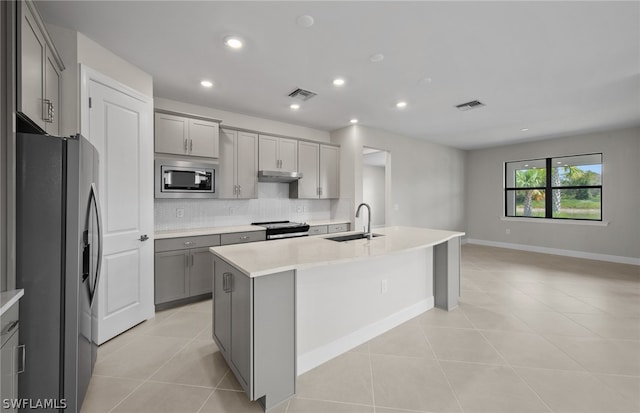 kitchen with stainless steel appliances, gray cabinets, a kitchen island with sink, sink, and light tile floors