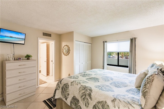 tiled bedroom with a textured ceiling and a closet