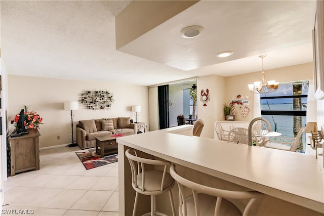 kitchen with a breakfast bar area, an inviting chandelier, pendant lighting, and light tile floors