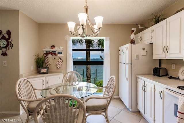 kitchen with light tile floors, white cabinets, a chandelier, a water view, and decorative light fixtures