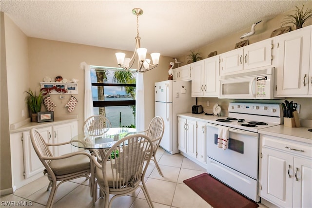 kitchen with white cabinetry, hanging light fixtures, light tile flooring, white appliances, and a notable chandelier