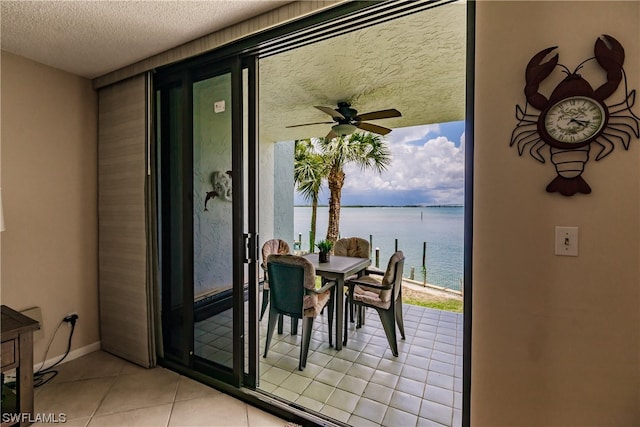 tiled dining area featuring plenty of natural light, ceiling fan, a textured ceiling, and a water view