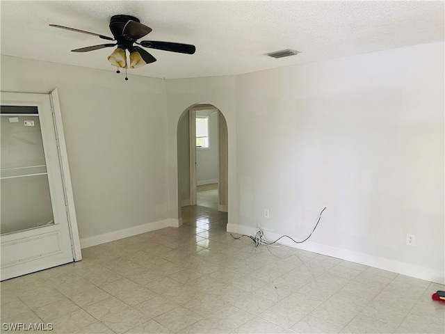 tiled empty room with a textured ceiling and ceiling fan