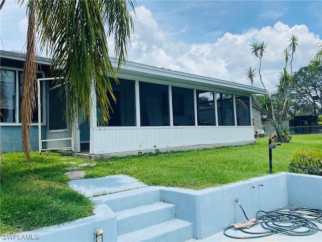 view of side of property with a sunroom and a lawn