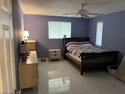 bedroom with light tile floors, ceiling fan, and a textured ceiling