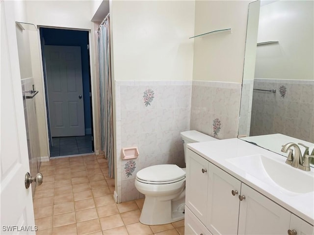 bathroom featuring vanity, toilet, tile patterned flooring, and tile walls