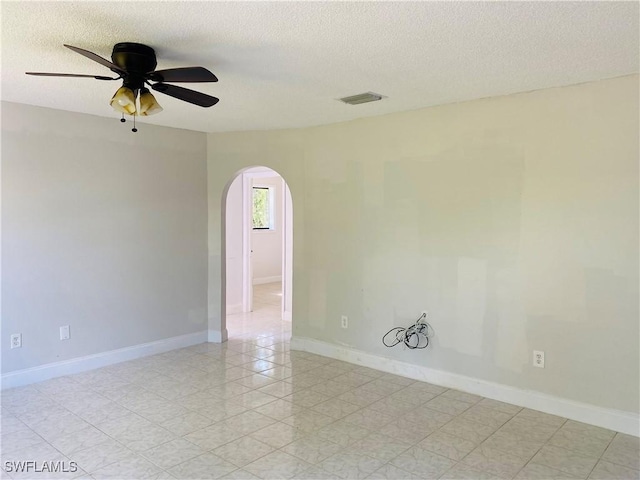 empty room with ceiling fan and a textured ceiling