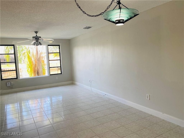 tiled empty room with ceiling fan and a textured ceiling