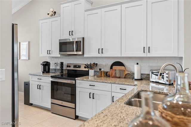 kitchen with lofted ceiling, white cabinetry, backsplash, appliances with stainless steel finishes, and light stone countertops