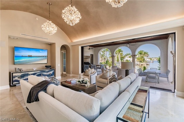 living room featuring a water view, high vaulted ceiling, and an inviting chandelier