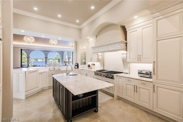 kitchen featuring stainless steel gas stovetop, decorative backsplash, crown molding, sink, and a kitchen island with sink