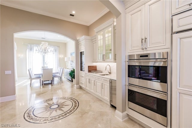 kitchen with white cabinetry, sink, ornamental molding, a chandelier, and double oven