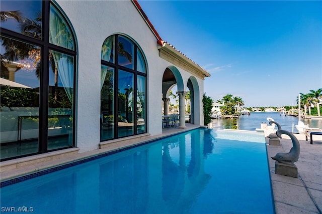 view of swimming pool with a patio area and a water view