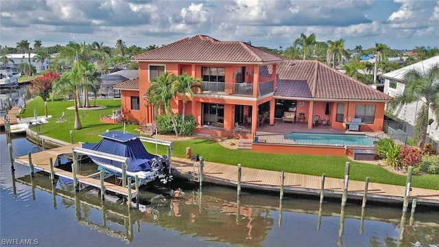 back of house featuring a patio area, a balcony, a water view, and a lawn