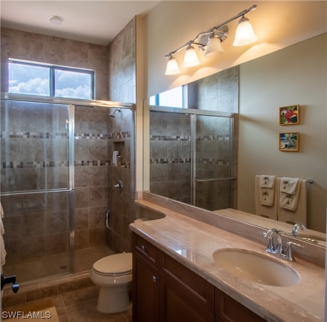 bathroom with a shower with door, toilet, tile patterned floors, and vanity