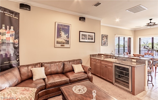 living room featuring indoor wet bar, ceiling fan, wine cooler, ornamental molding, and light tile patterned floors