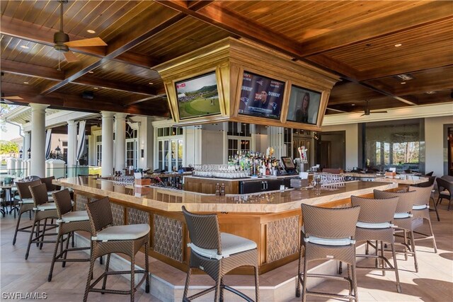 bar featuring ceiling fan, a wealth of natural light, wood ceiling, and decorative columns