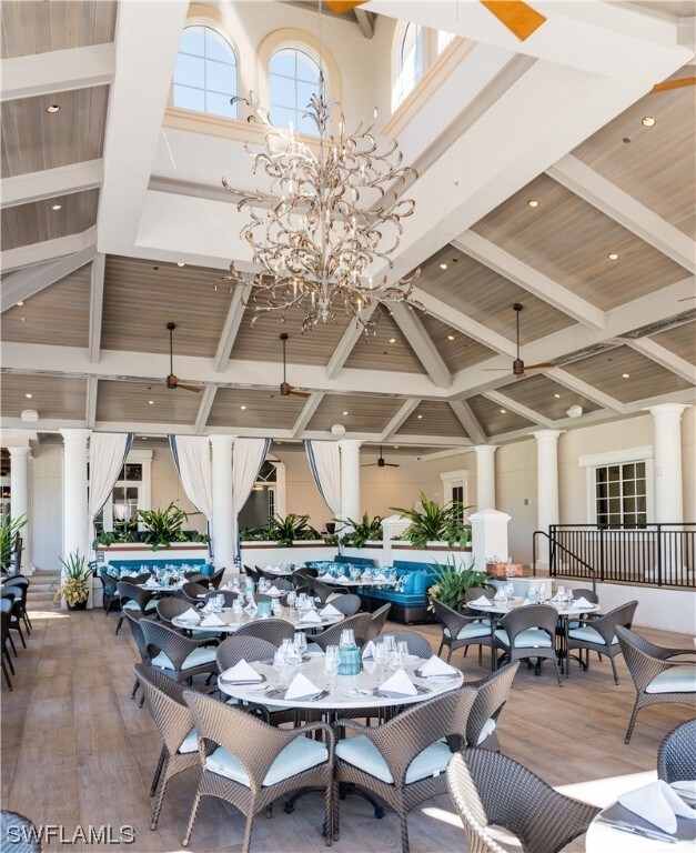 dining space with a towering ceiling, ceiling fan with notable chandelier, and hardwood / wood-style floors