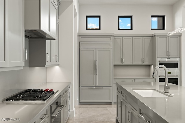 kitchen with sink, gray cabinets, wall chimney exhaust hood, and appliances with stainless steel finishes