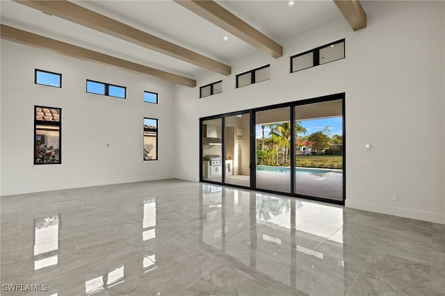 spare room featuring beamed ceiling and a towering ceiling