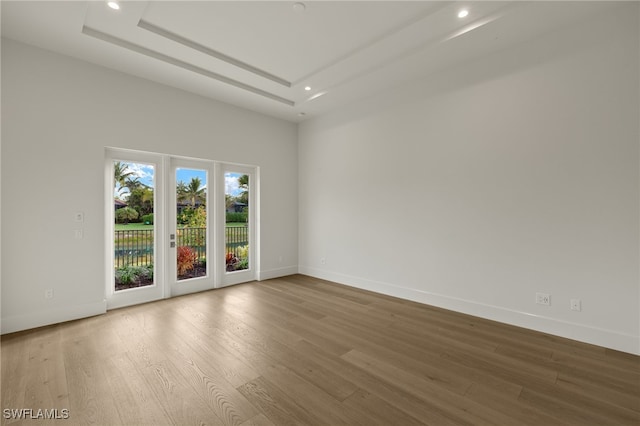 unfurnished room with hardwood / wood-style floors and a tray ceiling