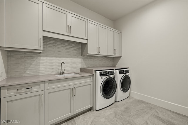 laundry room featuring sink, washing machine and dryer, and cabinets