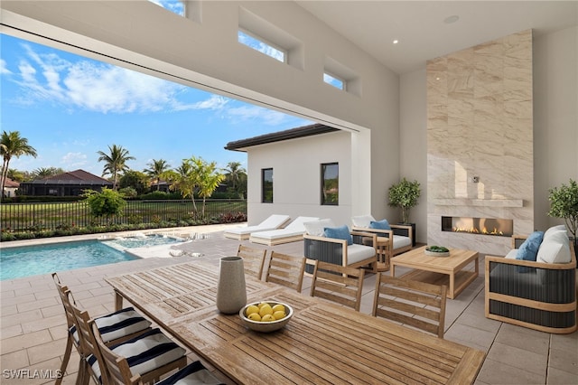 view of patio / terrace featuring a fenced in pool and an outdoor living space with a fireplace