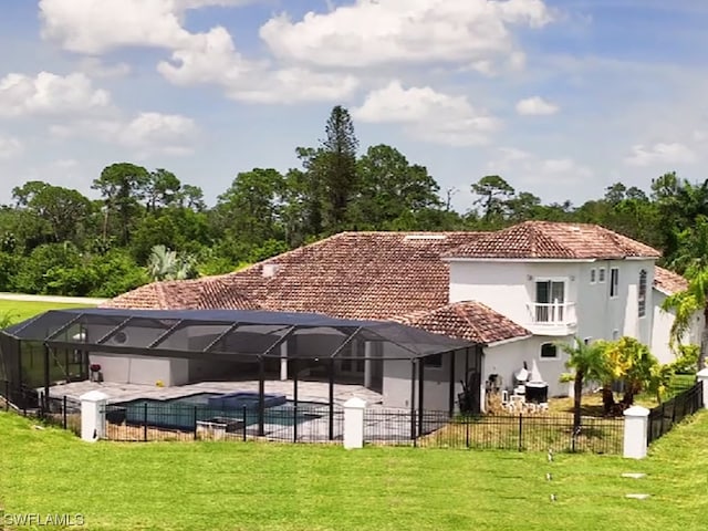 rear view of property featuring glass enclosure, a yard, and a fenced in pool