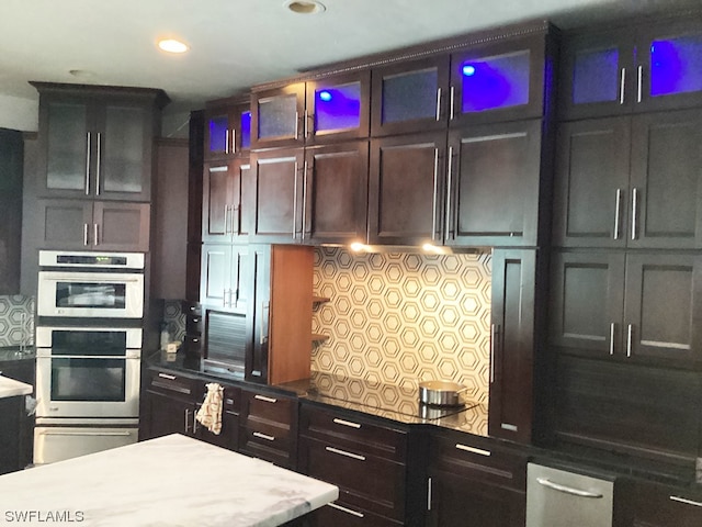 kitchen with stainless steel double oven, light stone countertops, and tasteful backsplash