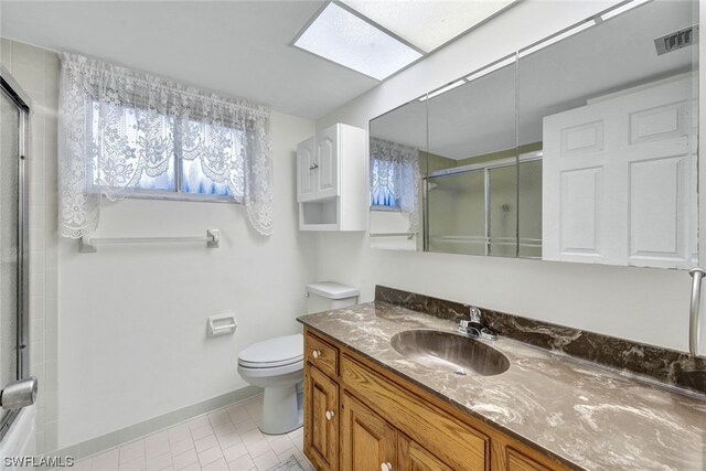 bathroom with vanity, toilet, a skylight, and a shower with door