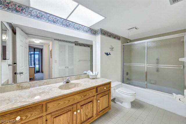 full bathroom featuring vanity, a skylight, bath / shower combo with glass door, and toilet