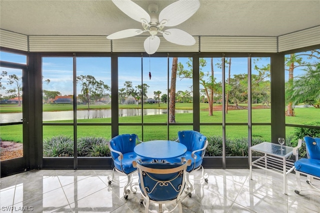 sunroom featuring ceiling fan and a water view