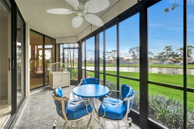 sunroom / solarium featuring a water view and ceiling fan