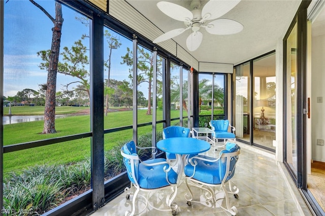 sunroom / solarium featuring ceiling fan and a water view