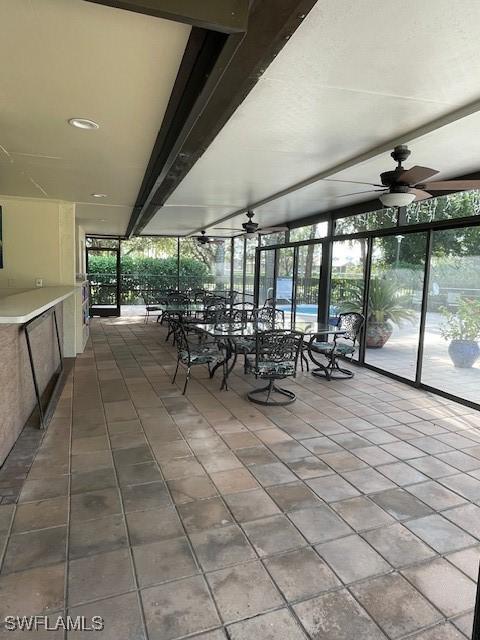 interior space featuring tile patterned flooring, ceiling fan, and a wall of windows