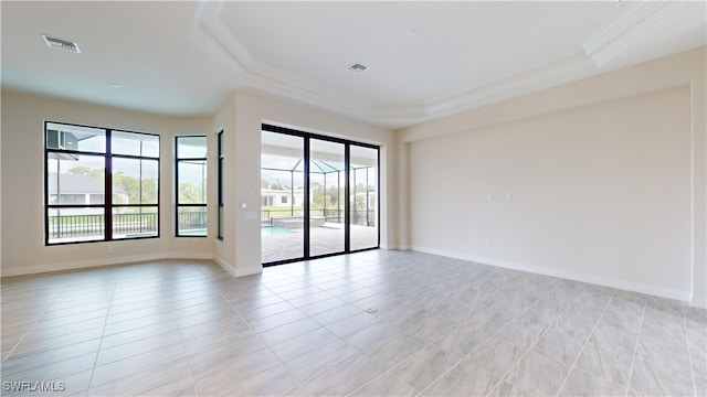 tiled empty room featuring a tray ceiling