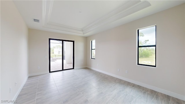 tiled spare room with crown molding and a tray ceiling